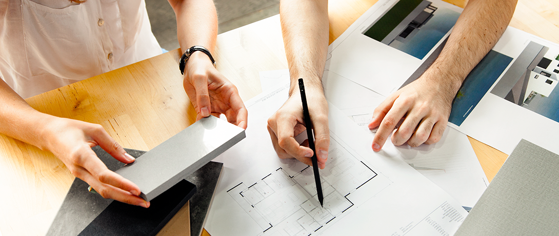 Dos manos y un plano de una casa